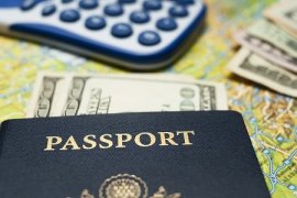 A passport, cash and a calculator sit on a map, indicating a travel budget.