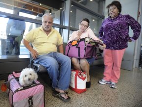 Tony Corrao, left, his wife, Victoria Torres, on the phone with customer service, and close friend Mayra Cuevas sit at the Portland International Jetport after being taken off a JetBlue flight Friday. Flight attendants told them their dog carrier was too large to fit completely under their seat, even though they flew to Portland with the carrier two other times with no problems.